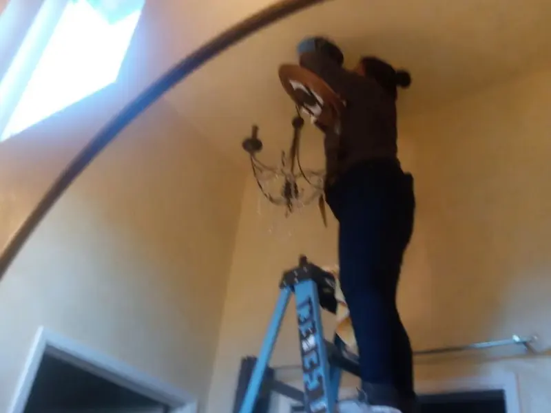 Electrician installing a chandelier in a Black Mountain residence